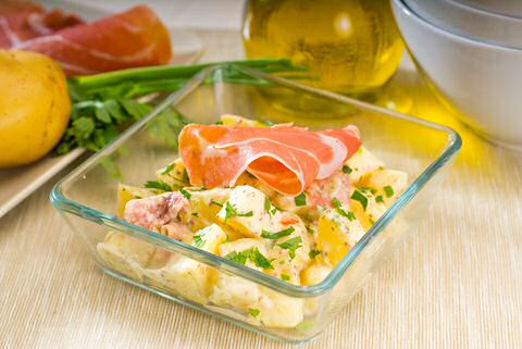 Aardappel salade gemaakt met vinaigrette van room, geserveerd met een blaadje basilicum, Parmezaan schilfers en Ganda ham